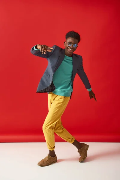 Positivo joven chico está bailando sobre fondo rojo — Foto de Stock