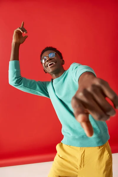 Feliz chico joven está bailando sobre fondo rojo — Foto de Stock