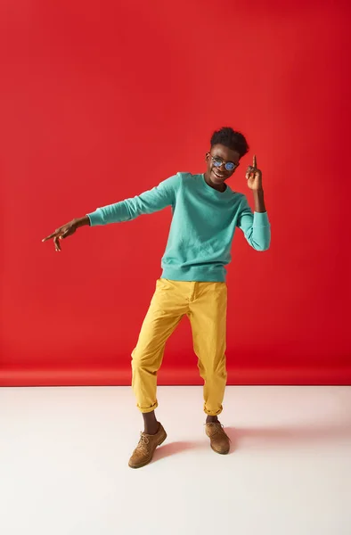 Chico positivo en gafas es bailando sobre fondo rojo — Foto de Stock