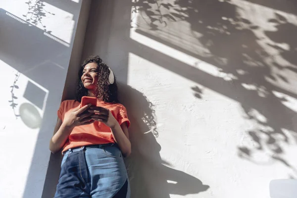 Grinning jovem mulher está ouvindo música dentro de casa — Fotografia de Stock