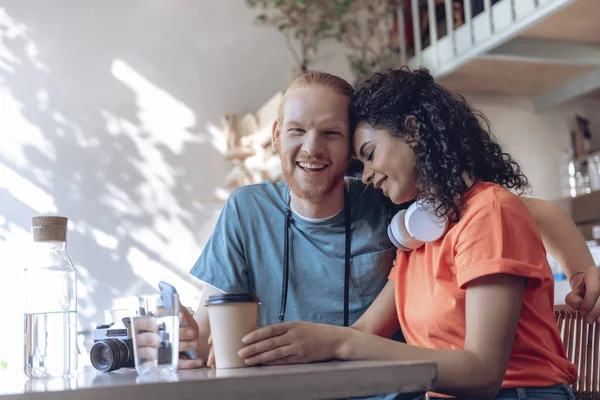 Happy guy is embracing girlfriend in cafe