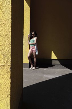 Sarı duvara yaslanmış kahve fincan ile Büyüleyici genç kadın