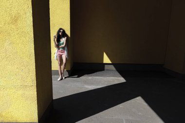 Sarı duvara yaslanmış kahve fincan ıslanan güzel genç kadın