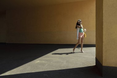 Sarı duvara karşı duran kulaklıkgüzel genç kadın