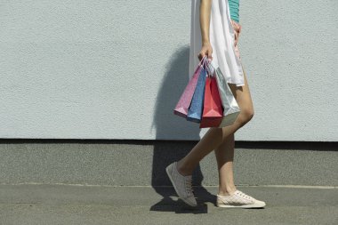Young woman in sneakers walking on the street after shopping
