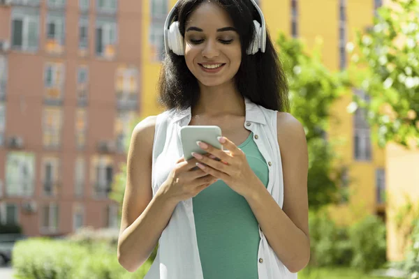 Belle fille brune dans un casque tenant un téléphone portable et profitant de la musique — Photo