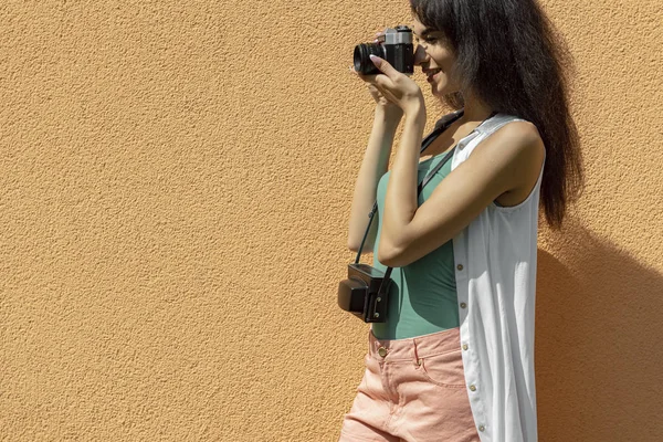 Charmig ung dam med retro kamera stående mot ljus orange vägg — Stockfoto