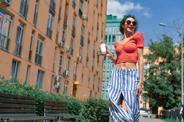 Sokakta duran take-away içki ile neşeli genç kadın