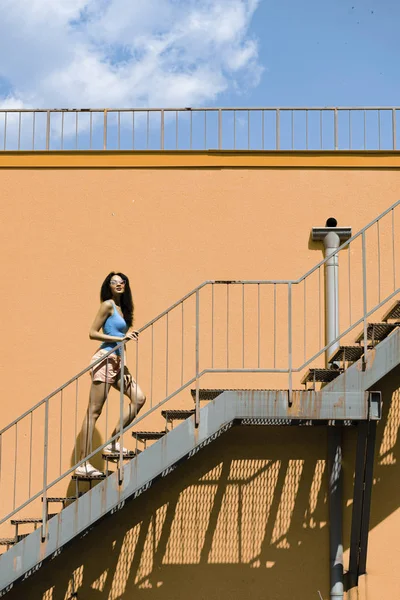 Çekici genç kadın sokakta merdivenlerden çıkıyor