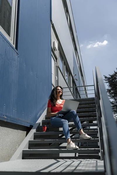 Encantadora joven con portátil sentado en las escaleras — Foto de Stock