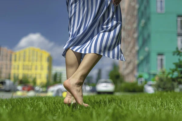 Mujer joven en falda a rayas caminando descalza sobre hierba —  Fotos de Stock