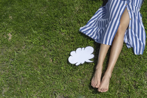 Fiatal nő csupasz lábbal feküdt zöld fű fehér gondolat buborék — Stock Fotó