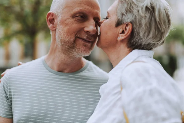 Glimlachend volwassen man en vrouw knuffelen buitenshuis — Stockfoto
