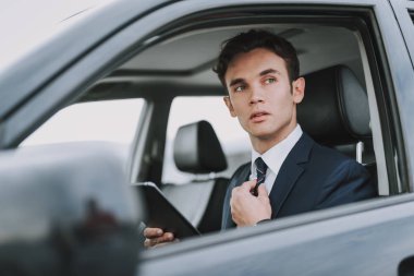 Genç yakışıklı adam tablet ile arabasında oturan