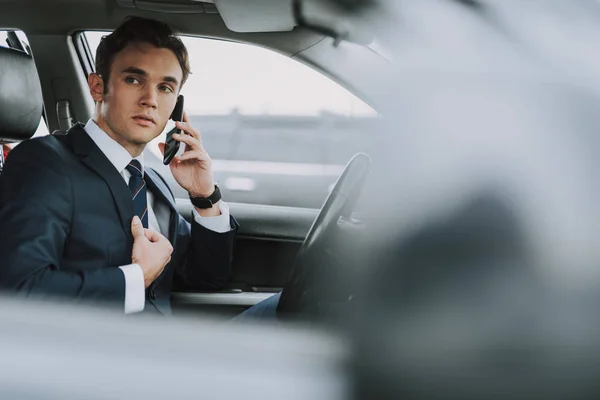 Junger Mann sitzt mit Smartphone im Auto — Stockfoto