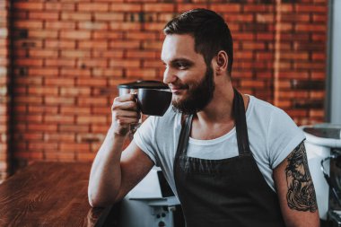 Sakallı barista bar tezgahına bir dirsek koyarak ve gülümseyerek