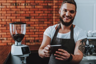 Neşeli barista ayakta ve gülümseyerek kahve bir fincan tutarken