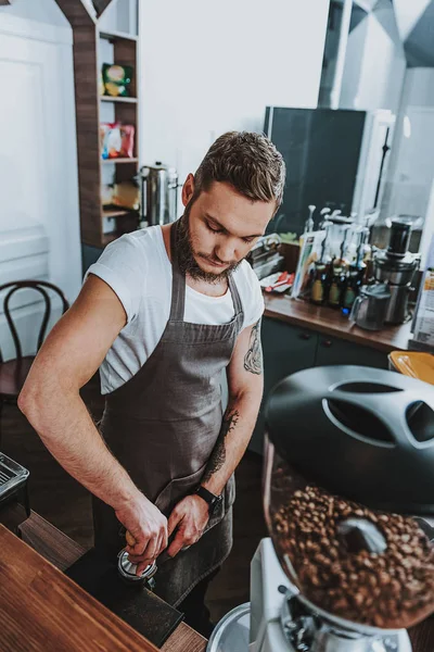 Cintura hacia arriba del barista concentrado de pie y presionando el café molido — Foto de Stock