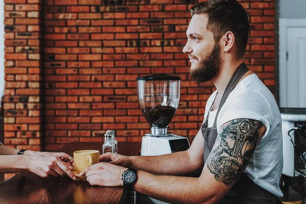 Uśmiechnięty Brodaty Barista dając kawę do swojego gościa — Zdjęcie stockowe