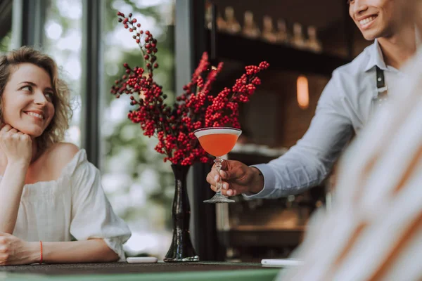 Schöner Barkeeper serviert jungen Frau Cocktail — Stockfoto