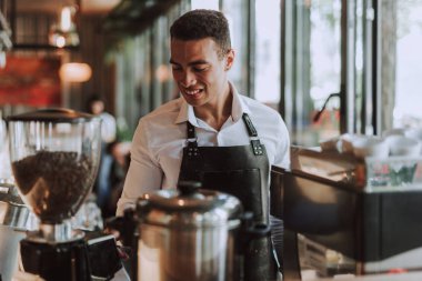 Siyah önlük yakışıklı barmen kahve dükkanında çalışıyor