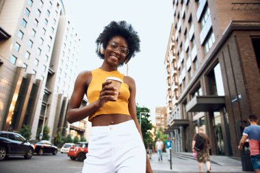 Sokakta kahve tutan gülümseyen genç bayan