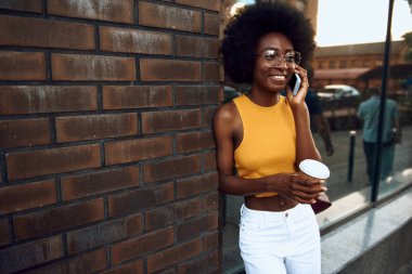 Gözlük gülümseyen afro-amerikan bayan açık havada akıllı telefon kullanıyor