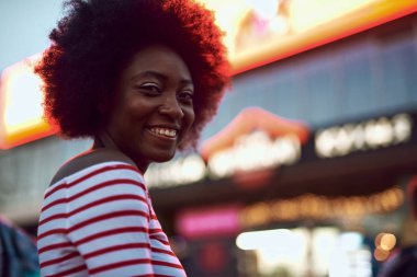 Neşeli afro-amerikan bayan sokakta gülümseyerek bakıyor