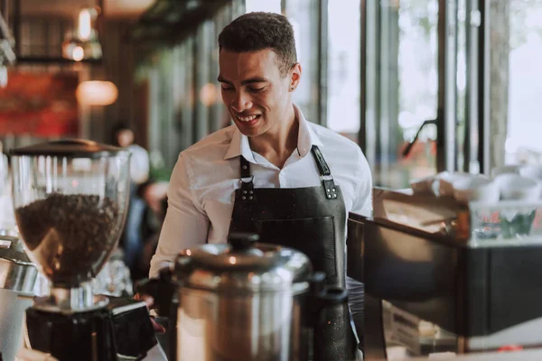Guapo barman en delantal negro trabajando en cafetería — Foto de Stock