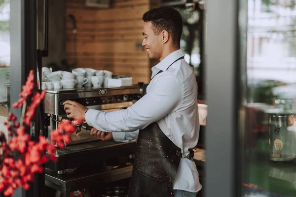 Barman guapo en delantal negro usando máquina de café profesional —  Fotos de Stock