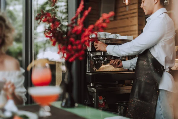 Barman souriant en tablier noir utilisant une machine à café professionnelle — Photo