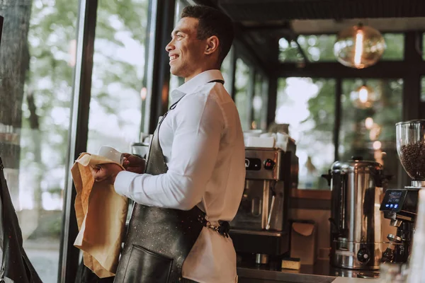 Barman alegre taza de limpieza con paño de limpieza en la cafetería —  Fotos de Stock