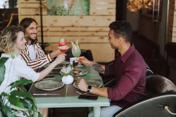Amigos alegres brindando con cócteles mientras pasan tiempo en la cafetería —  Fotos de Stock