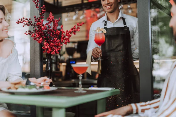 Симпатичный бармен, подающий коктейль посетителям кафе на открытом воздухе — стоковое фото