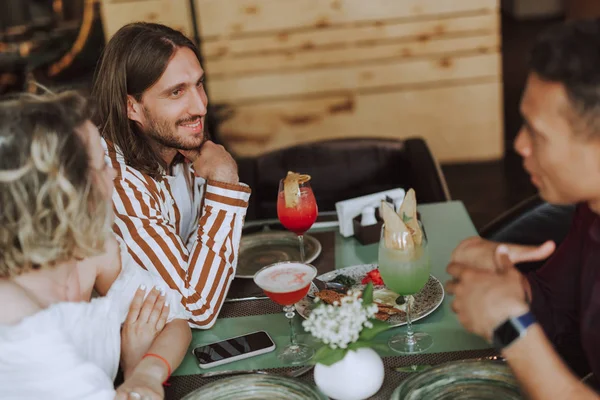 Troje przyjaciół rozmawiając i delektując się koktajlami w kawiarni — Zdjęcie stockowe