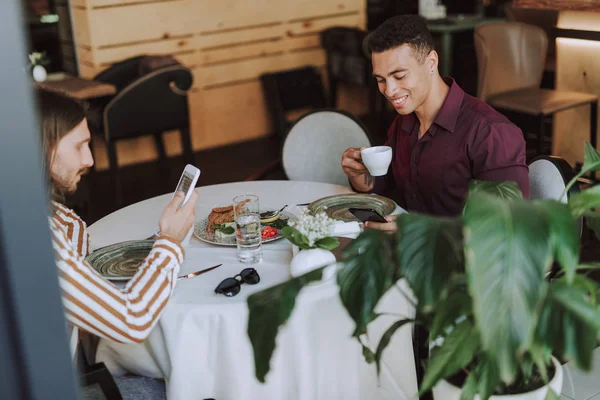 Två män dricker kaffe och använder mobiltelefoner i Café — Stockfoto