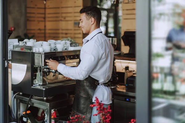 Barman sonriente en delantal negro usando máquina de café profesional —  Fotos de Stock