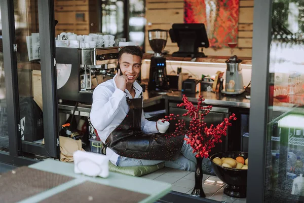 Barman joyeux avec boisson chaude parler sur téléphone portable dans le café — Photo