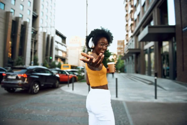 Happy afro-american woman holding coffee on the street and smiling — Stock Photo, Image