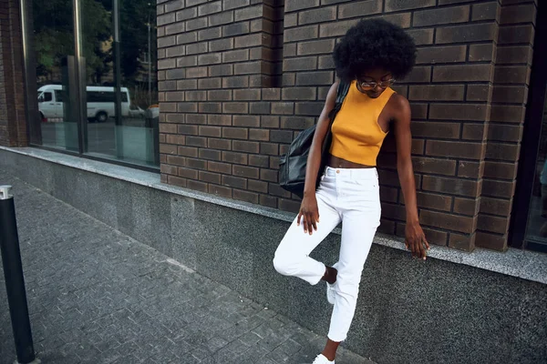 Genç afro-Amerikan kadın şehirde tuğla duvar yakınında dinlenme