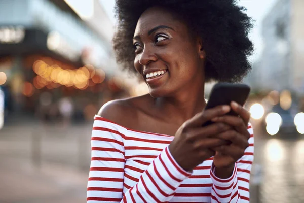 Joyeuse jeune femme utilise smartphone en plein air — Photo