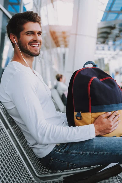 Joven alegre está esperando en la parada de autobús — Foto de Stock