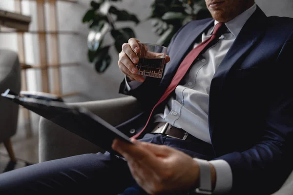 Hombre en traje sosteniendo la carpeta con documentos mientras está sentado solo — Foto de Stock