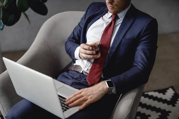 Hombre de traje y corbata usando laptop y bebiendo alcohol — Foto de Stock