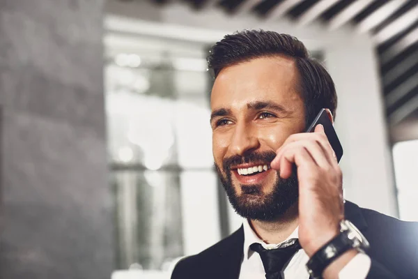 Primer plano del joven guapo hablando por teléfono y sonriendo —  Fotos de Stock