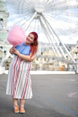 Pamuk şeker ile şehirde yürüyen genç şişman kadın