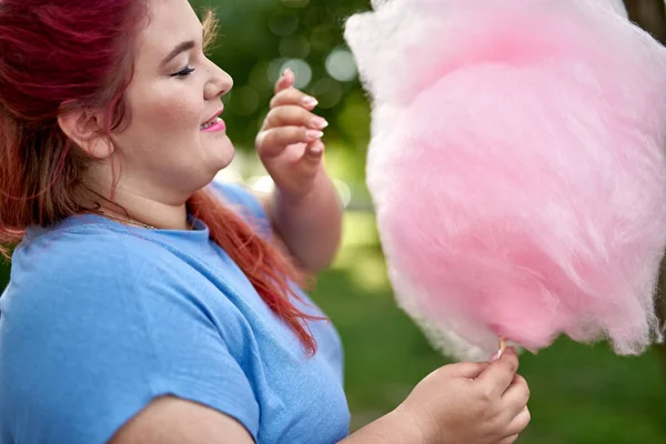 Mulher jovem e gorda olhando para algodão doce — Fotografia de Stock