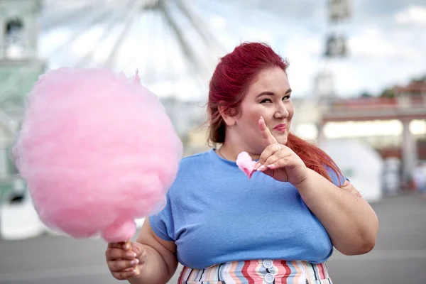 Dicke junge Frau mit Zuckerwatte, die mit dem Finger zeigt — Stockfoto