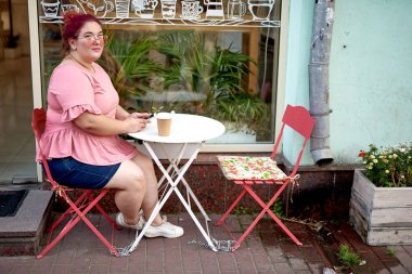 Şişman genç kadın kafede akıllı telefon kullanıyor