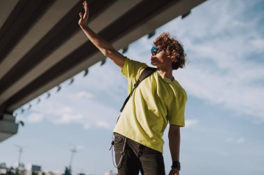 Kıvırcık genç adam elini öne koyarak ve güneşten gizleme